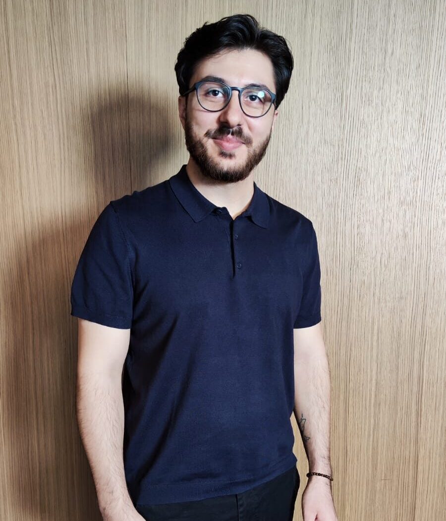 Serdah, Tech-Spezialist bei Ipsom, trägt ein dunkelblaues Poloshirt und steht freundlich lächelnd im Teamfoto