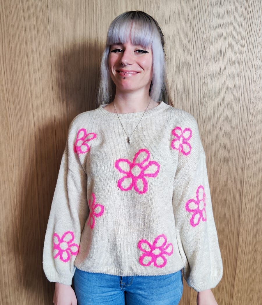Chrissi vom Ipsom-Team mit blondem Pony, hellem Pulli mit pinken Blumen – zuständig für Content und Design

